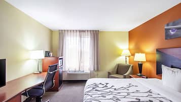 A hotel room with a bed, desk, chair, and a window with curtains.