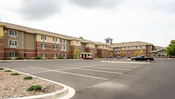 A hotel with a parking lot, multiple buildings, and a few cars parked.