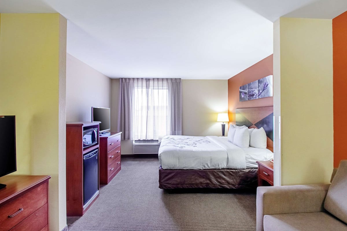 A hotel room with a bed, a TV, a desk, and a chair.
