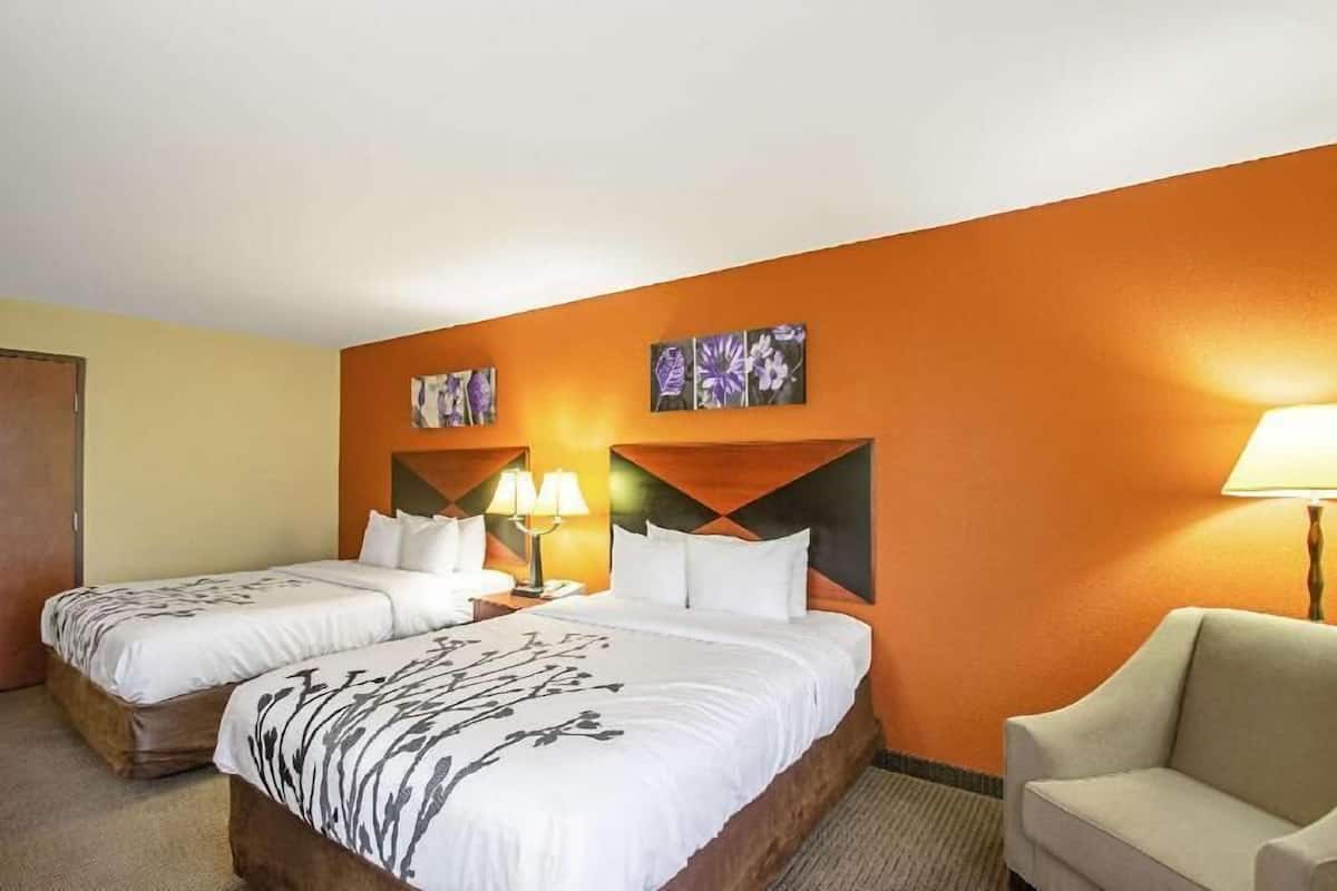 A hotel room with two beds, a sofa, and artwork on the walls.