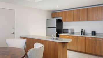A modern kitchen with wooden cabinets, a stainless steel refrigerator, a microwave, and a coffee maker.