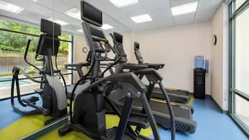 A gym with treadmills, elliptical machines, and a water dispenser.