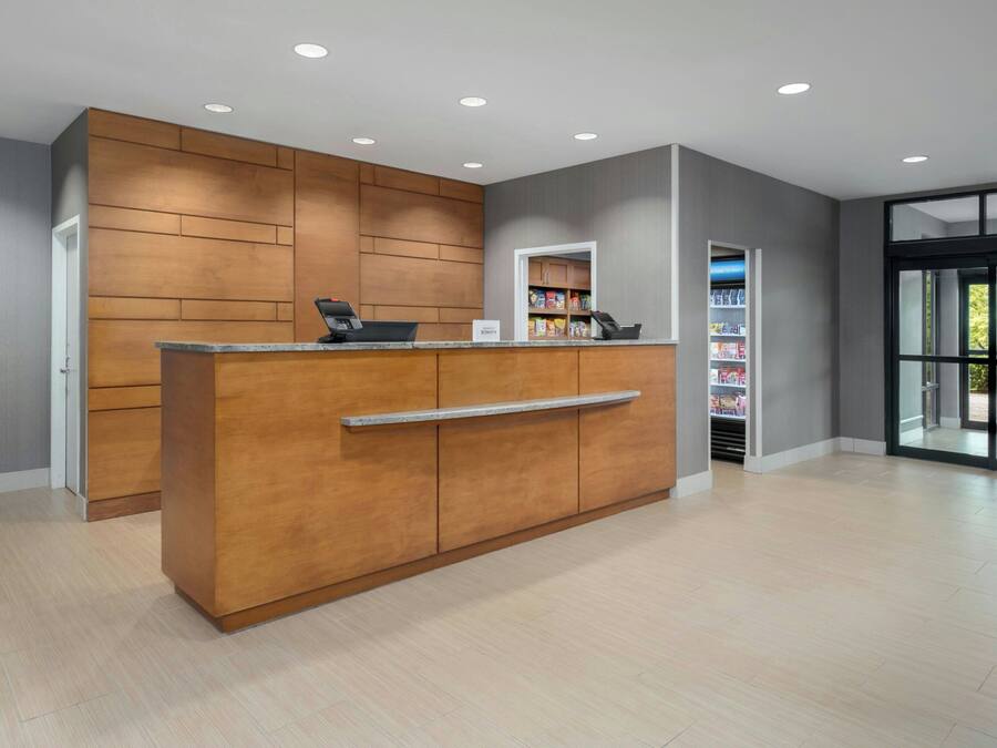 A reception desk with a wooden finish, a counter, and a shelf with snacks.