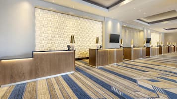 En hotellobby med en vägg som har ett mönster, flera receptionsdiskar och en mönstrad matta.
