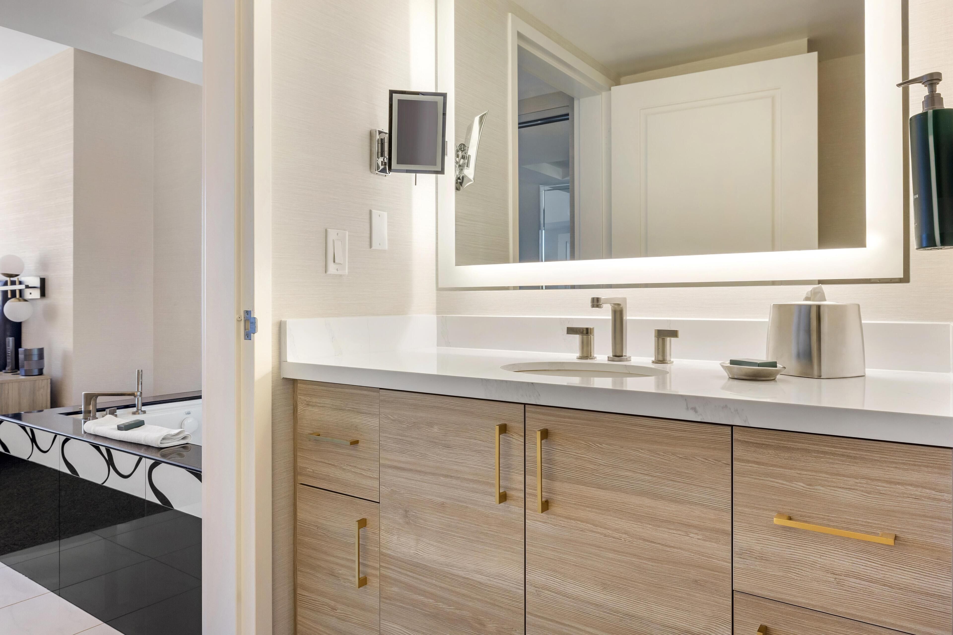 A modern bathroom with a large mirror, a sink, and wooden cabinets.