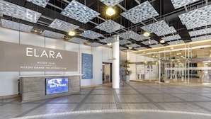 A modern hotel lobby with a large reception desk, a digital display, and a unique ceiling design.