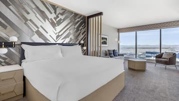 Habitación de hotel moderna con una cama grande, un escritorio, una silla y vistas a la ciudad.