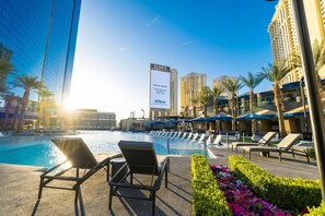 Un espace piscine d’hôtel avec des chaises longues et un grand panneau publicitaire faisant la promotion de l’hôtel Hilton.