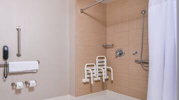 A shower area with a wooden wall, a grab bar, a showerhead, and a towel rack.