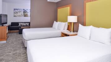 A hotel room with two beds, a TV, a sofa, and a painting on the wall.