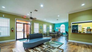 A spacious lobby with a curved blue sofa, a glass coffee table, and a dining area with chairs and tables. - Quality Inn DeRidder (DeRidder)