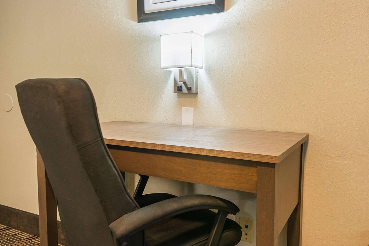A wooden desk with a black office chair.