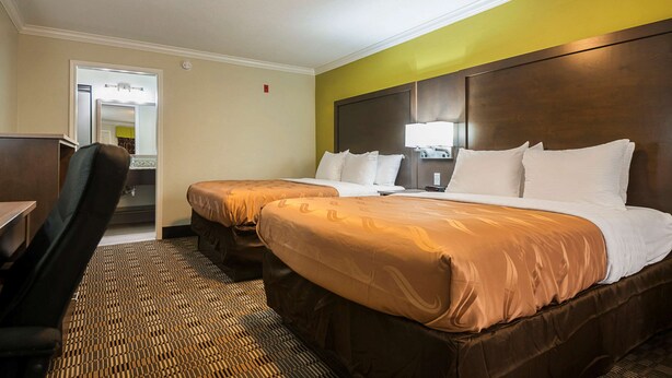 A hotel room with two beds, a desk, and a chair. - Quality Inn DeRidder (DeRidder)