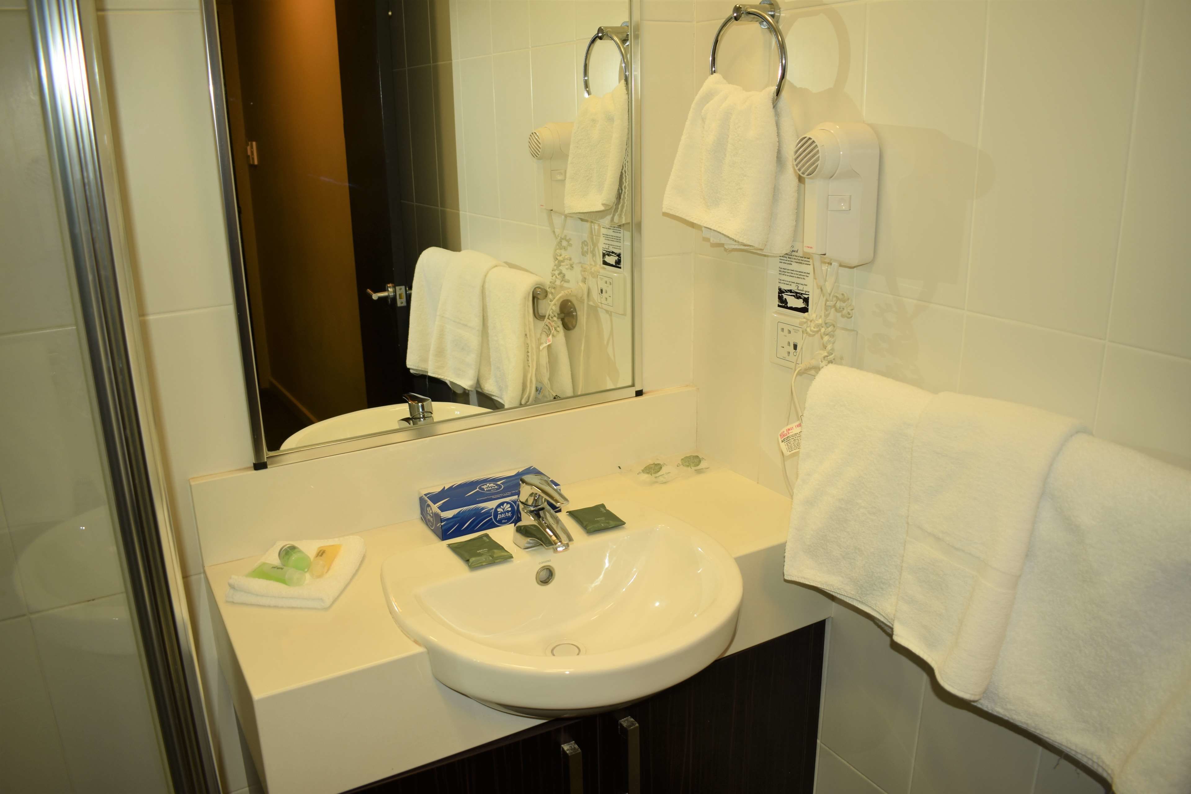 A bathroom with a white sink, a mirror, and two towel hooks.