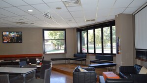 A spacious indoor area with multiple seating options including tables, chairs, and couches. There are large windows providing natural light and views of the outdoors. - Best Western Blackbutt Inn (New Lambton)
