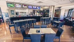 A restaurant with a bar area, multiple screens displaying content, and a variety of seating arrangements including tables and chairs. - Best Western Blackbutt Inn (New Lambton)