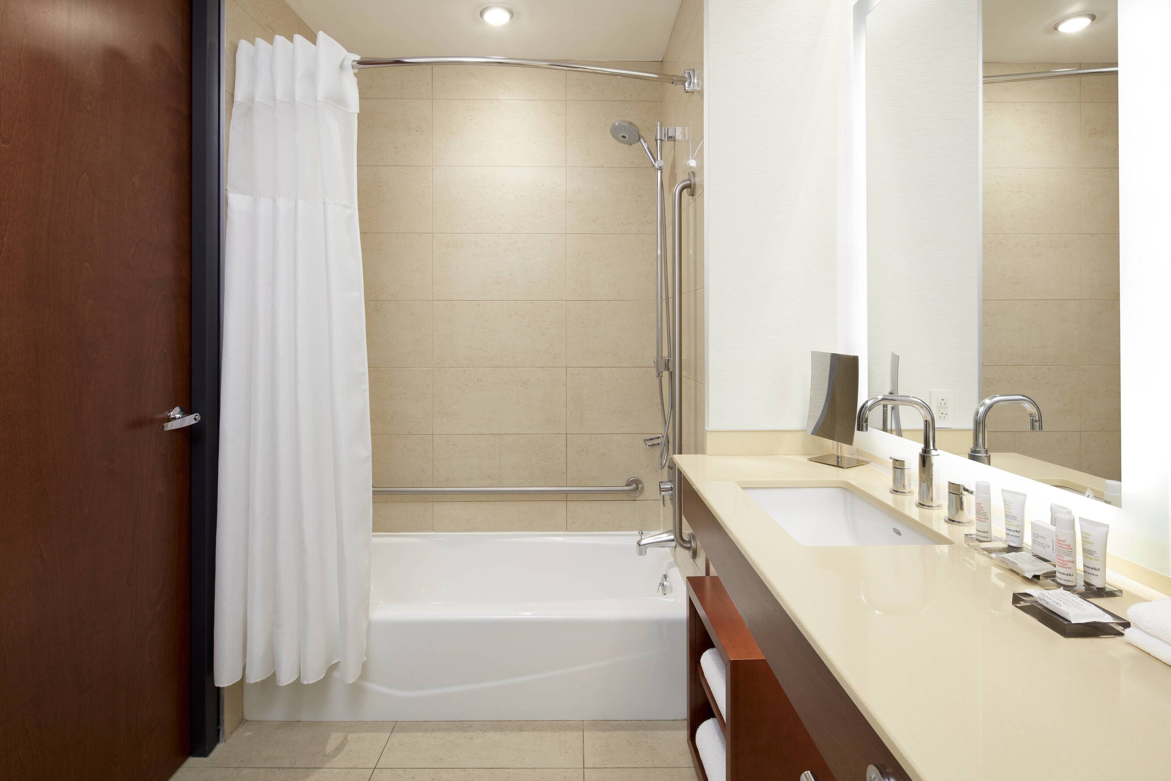 A modern bathroom with a bathtub, shower, and dual sinks.
