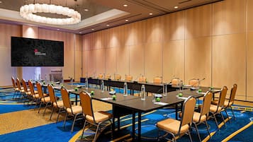 A conference room with a long table, chairs, a large screen, and a carpeted floor.