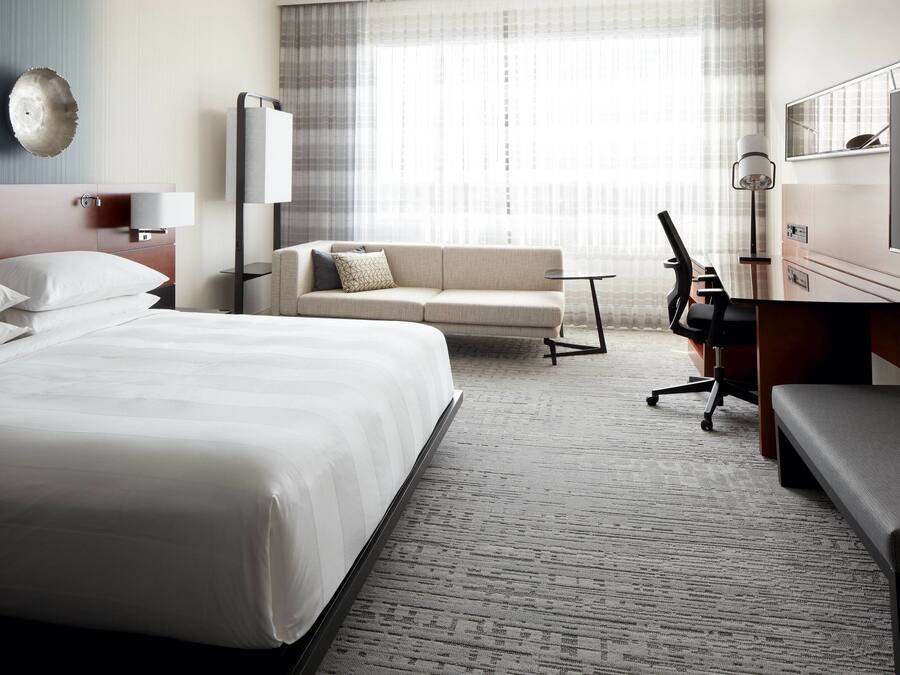 Een hotelkamer met een groot bed, een slaapbank, een bureau met een stoel en een televisie.