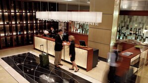 A hotel reception area with a modern design, featuring a reception desk, a waiting area, and a decorative wall with shelves. - Montreal Airport Marriott In-Terminal Hotel (Dorval)