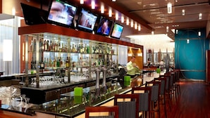 A bar area with multiple screens, a well-stocked liquor shelf, and a seating area with chairs. - Montreal Airport Marriott In-Terminal Hotel (Dorval)