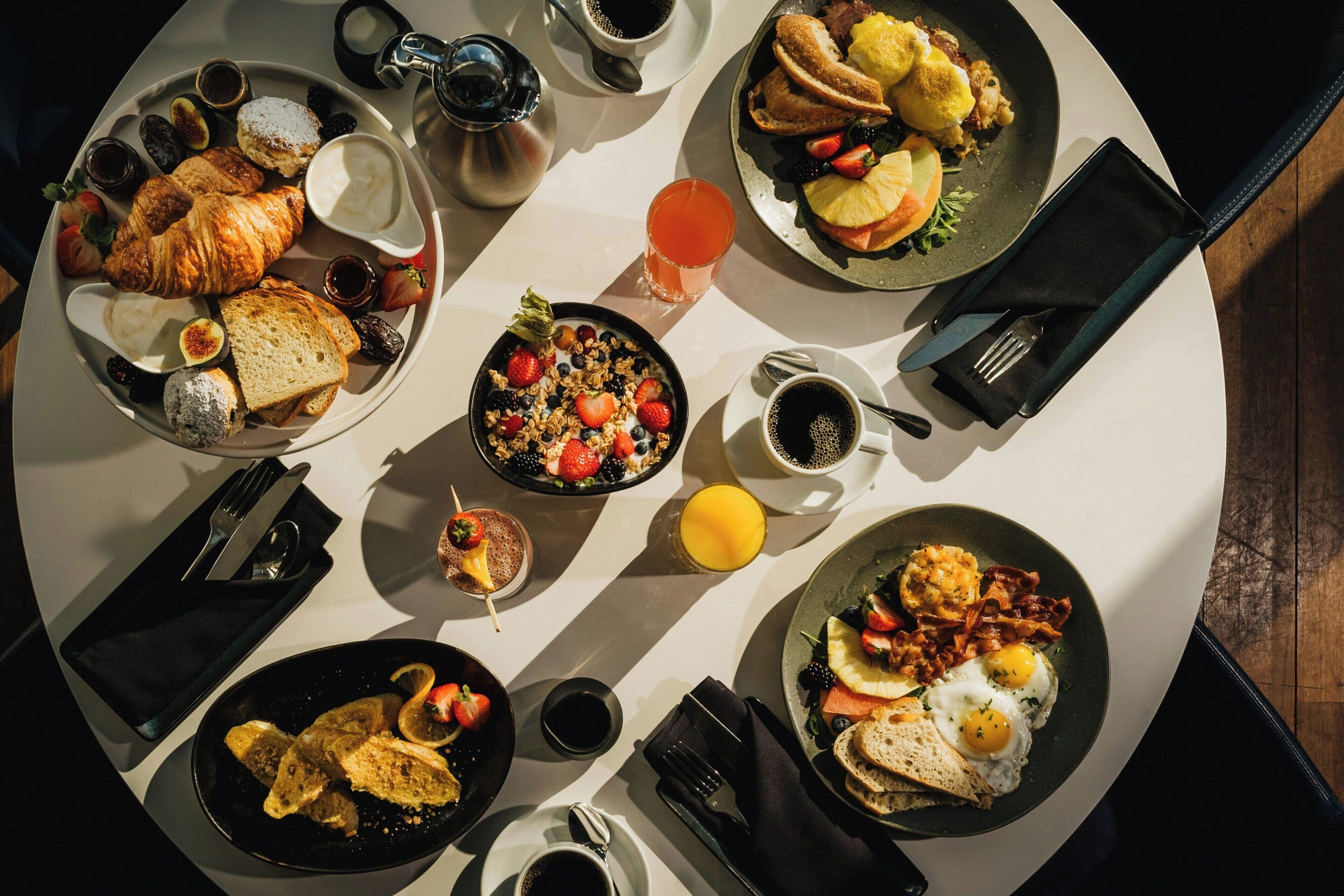 A breakfast buffet with various dishes, including croissants, fruits, and eggs.