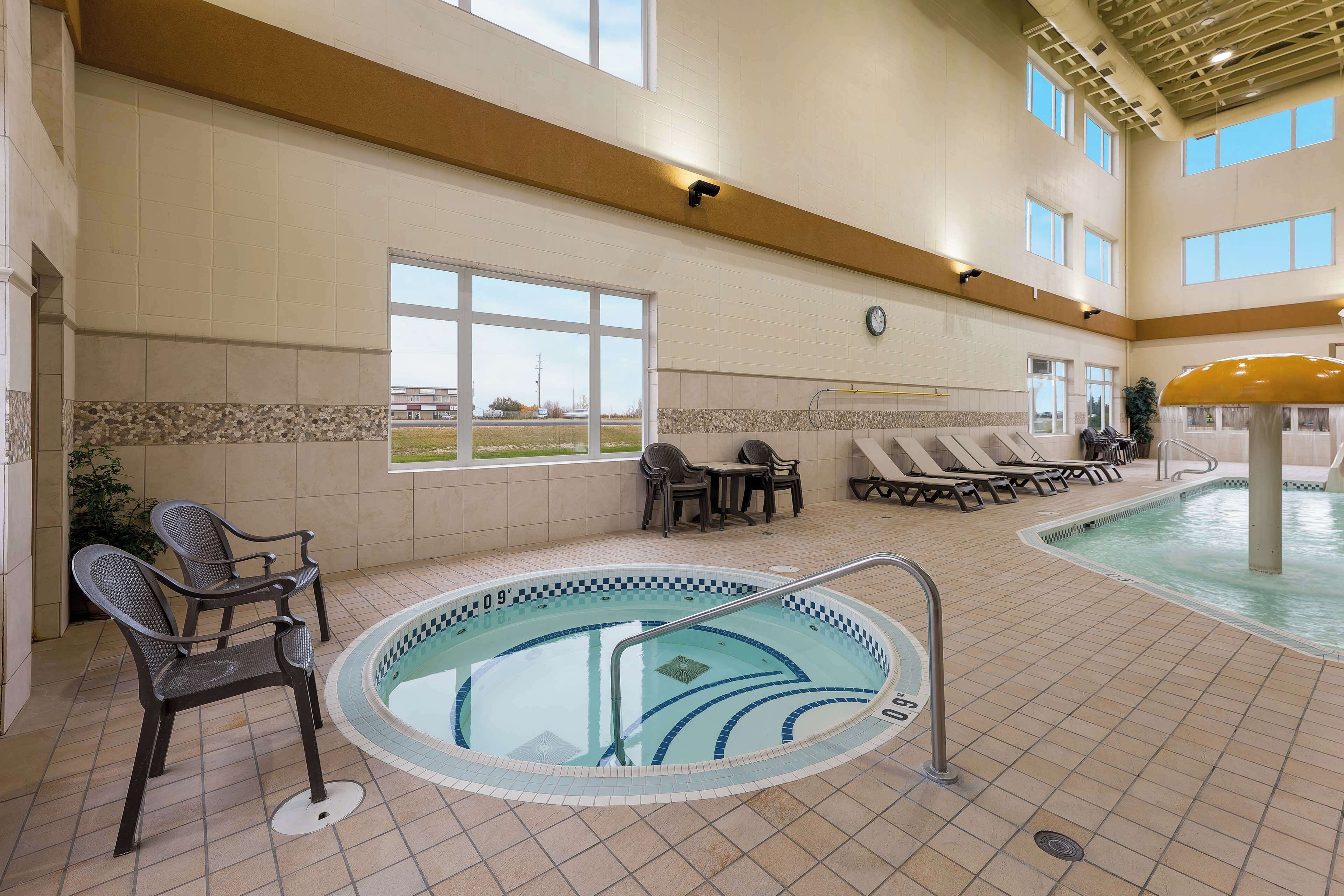 An indoor swimming pool with lounge chairs and a sunbathing area.