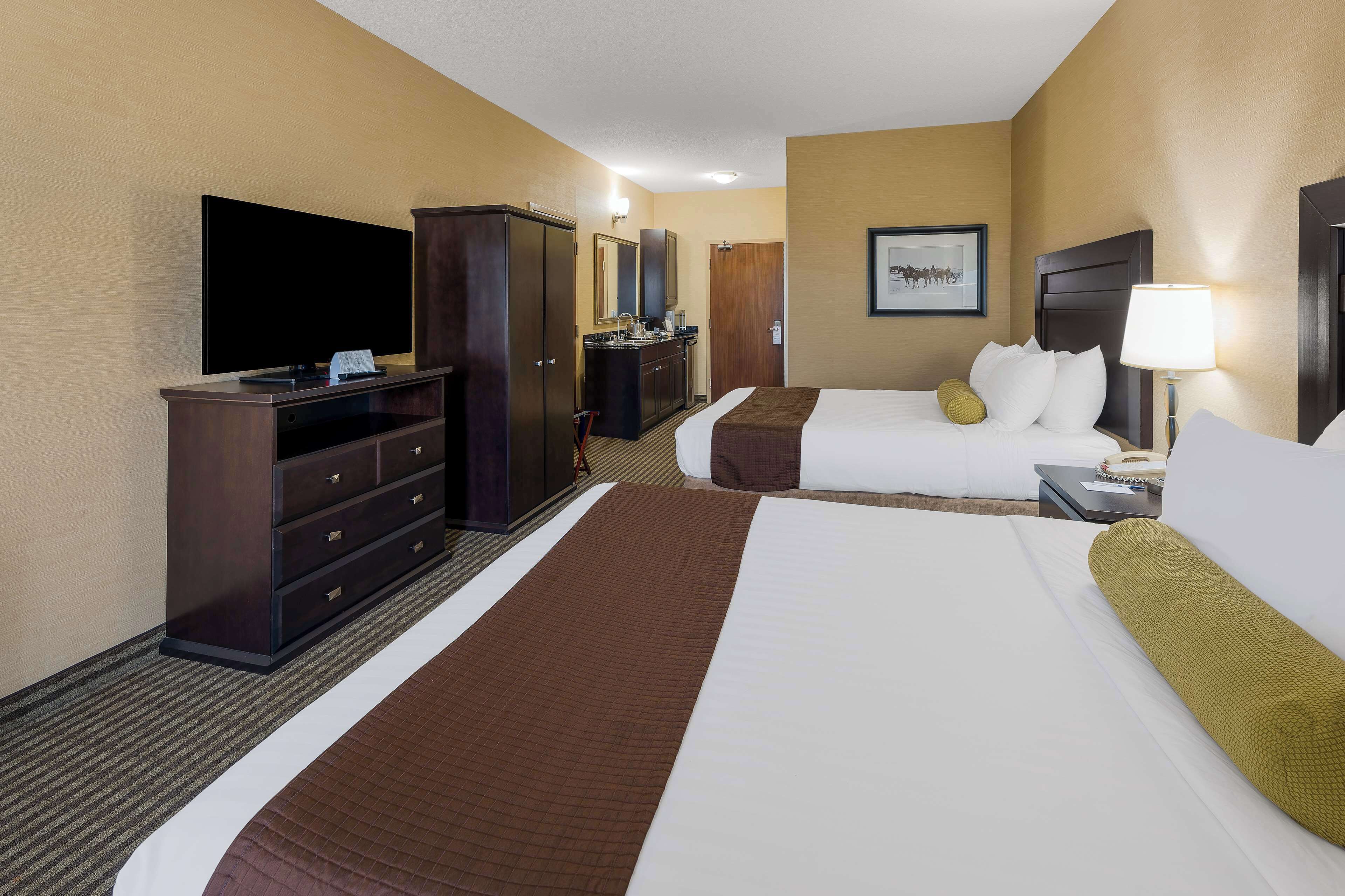 Een hotelkamer met een groot bed, een televisie, een bureau met lamp en een kledingkast.