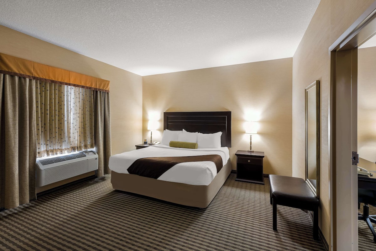 A hotel room with a large bed, bedside tables, a desk, and a chair.