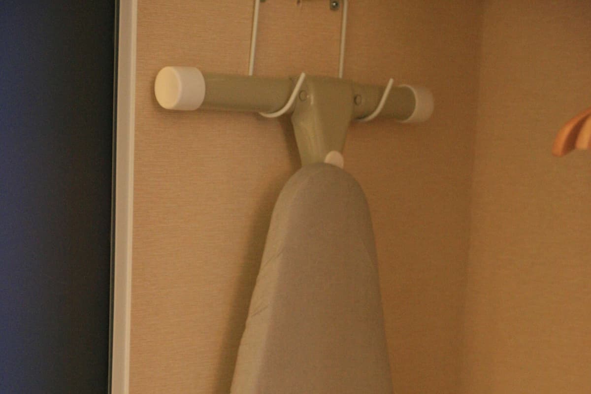 Una tabla de planchar abatible en una habitación con paredes color beige.