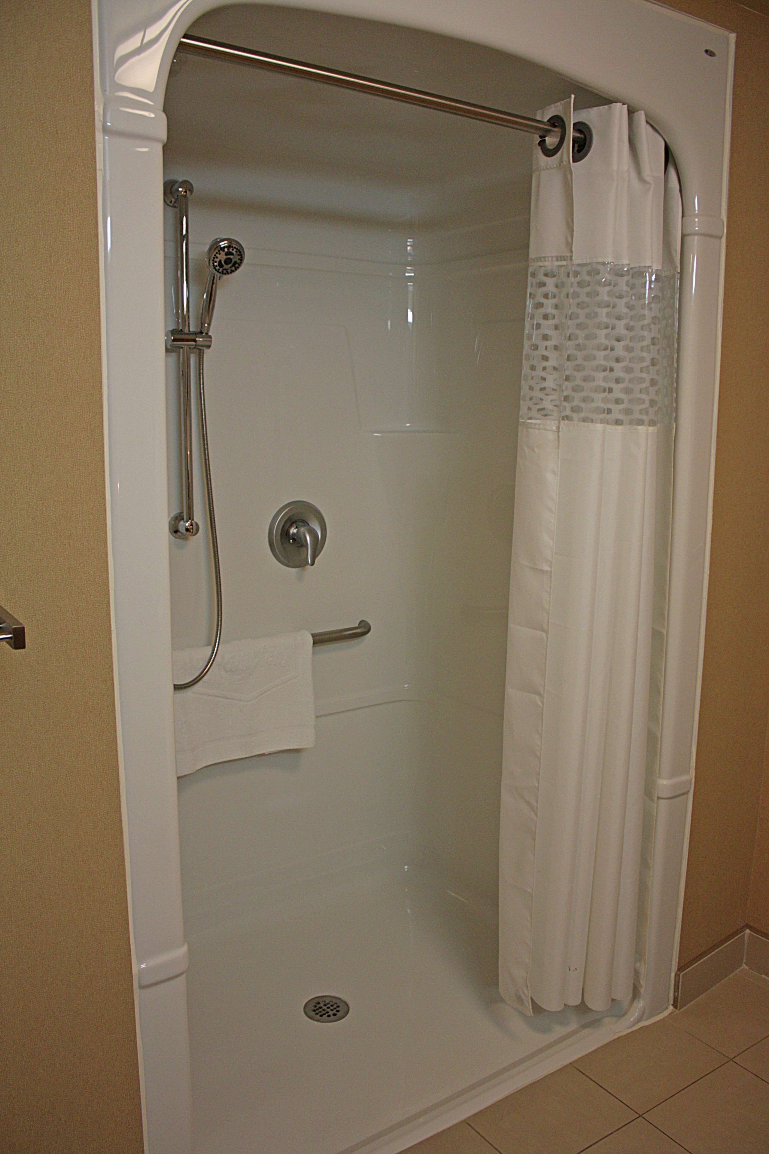 A walk-in shower with a glass door, a handheld showerhead, and a towel rack.