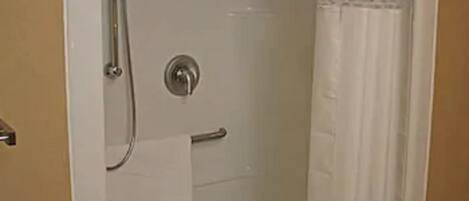 A bathroom with a shower, a towel rack, and a toilet paper holder.
