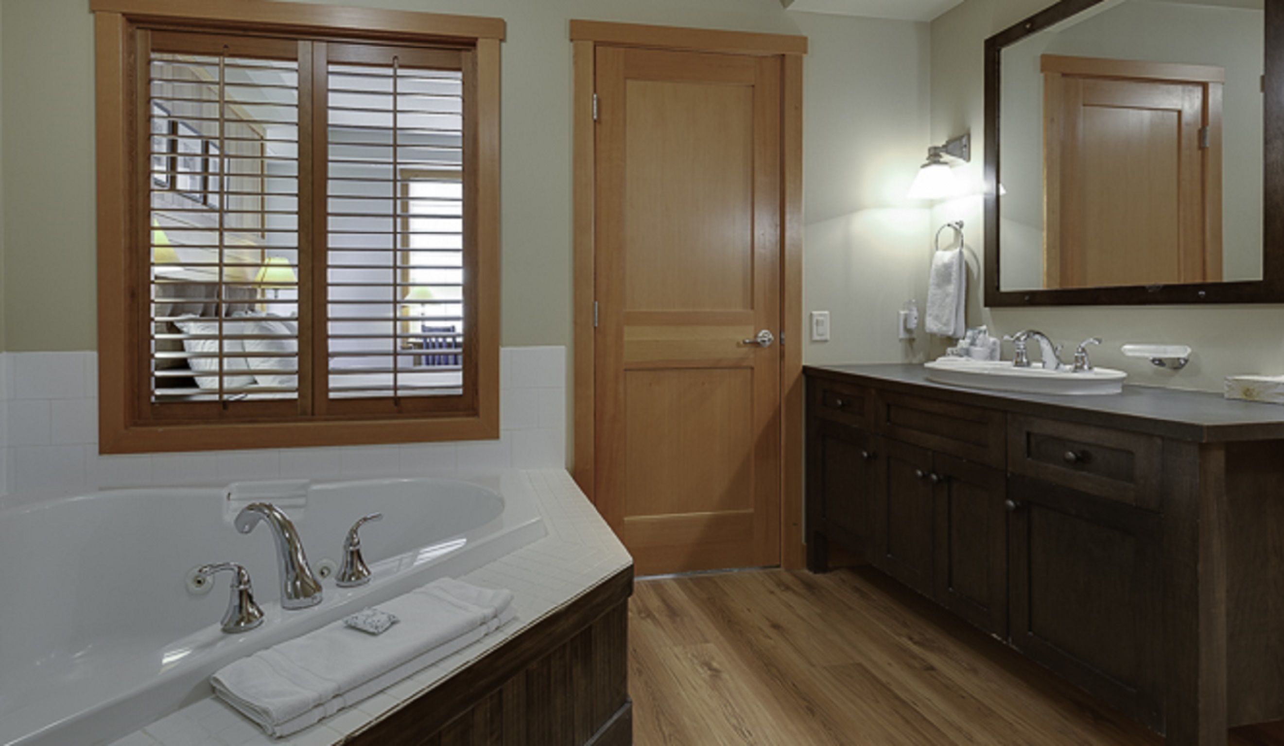 A bathroom with a large bathtub, a double sink vanity, and a wooden door.