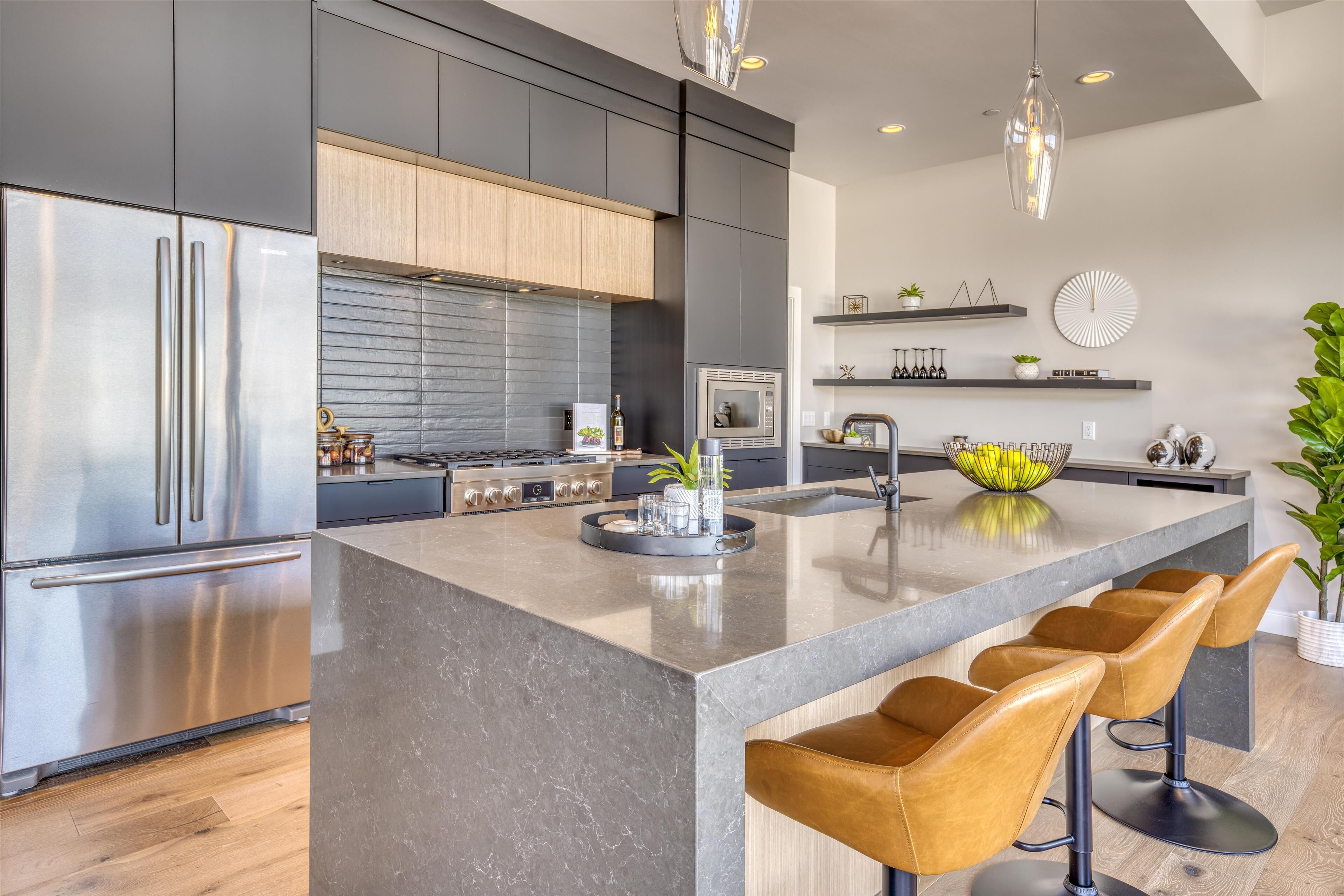 A modern kitchen with stainless steel appliances, a central island with bar stools, and a minimalist design.