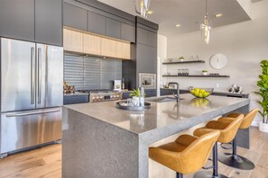 A modern kitchen with stainless steel appliances, a central island with bar stools, and a minimalist design.