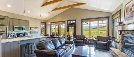A spacious living area with a fireplace, leather sofas, and a kitchen with a large island.