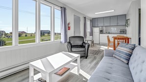 A modern living room with a grey sofa, a white coffee table, and a view of the outdoors. - Mavillette Beach Lodge and RV Park (Mavillette)