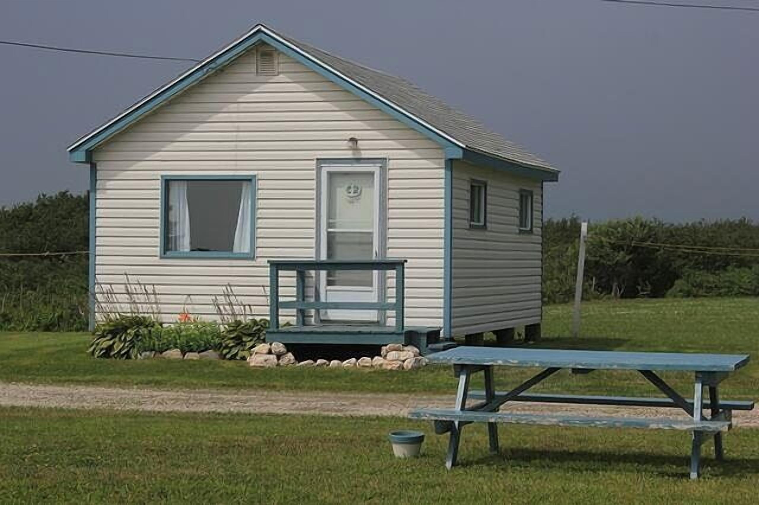 A small, single-story cabin with a porch and a picnic table in front.