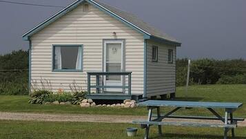 A small, single-story cabin with a porch and a picnic table in front.