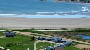 A coastal village with a sandy beach, a small harbor, and several buildings including a large house with a flag. - Mavillette Beach Lodge and RV Park (Mavillette)