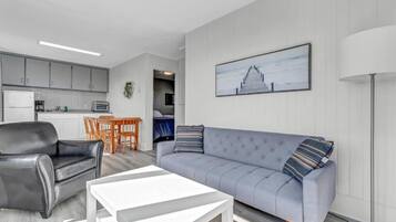 Ein modernes Wohnzimmer mit einem grauen Sofa, einem schwarzen Ledersessel und einem weißen Couchtisch.