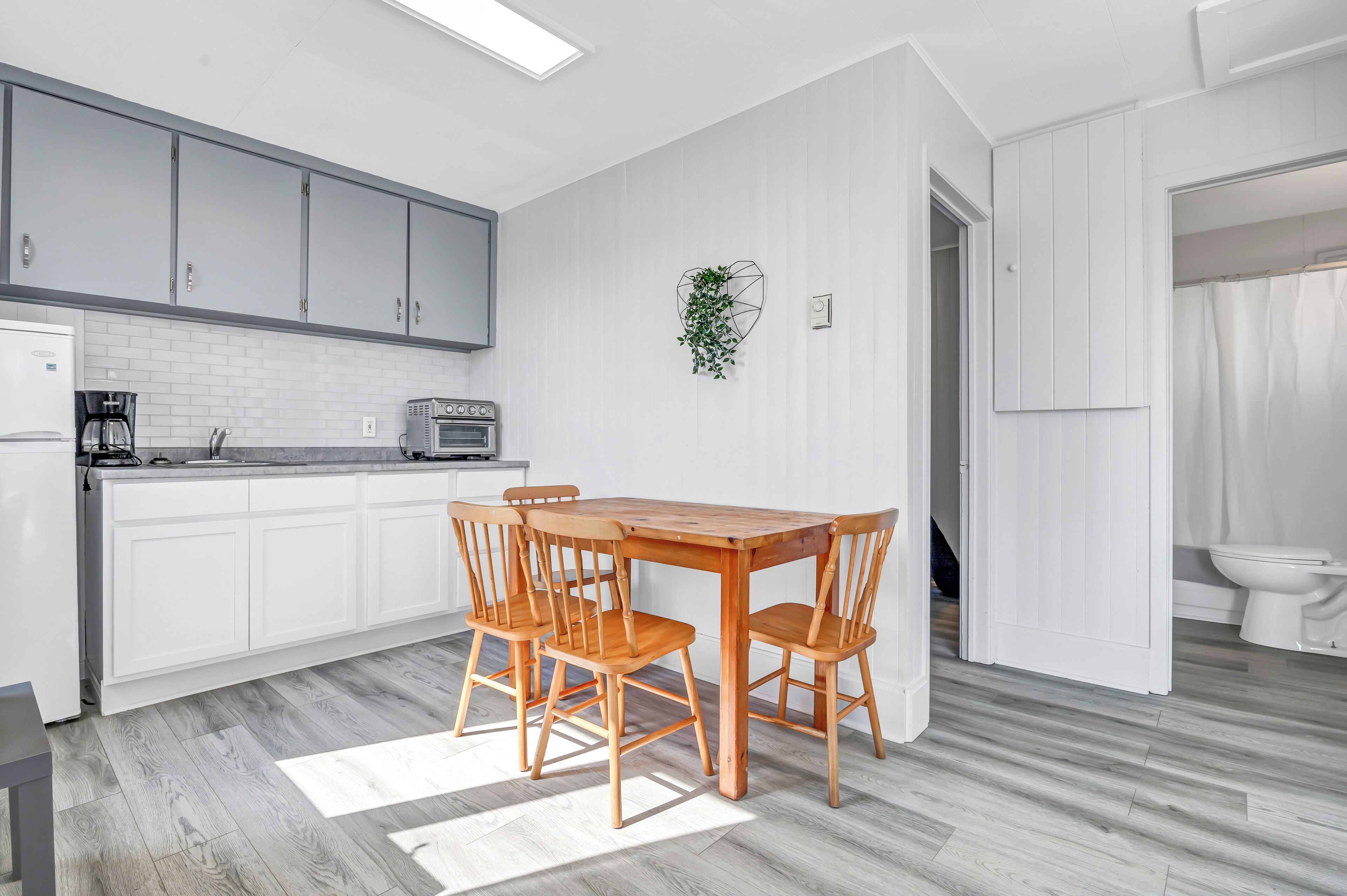 A modern kitchen with white cabinetry, a wooden dining table, and chairs.