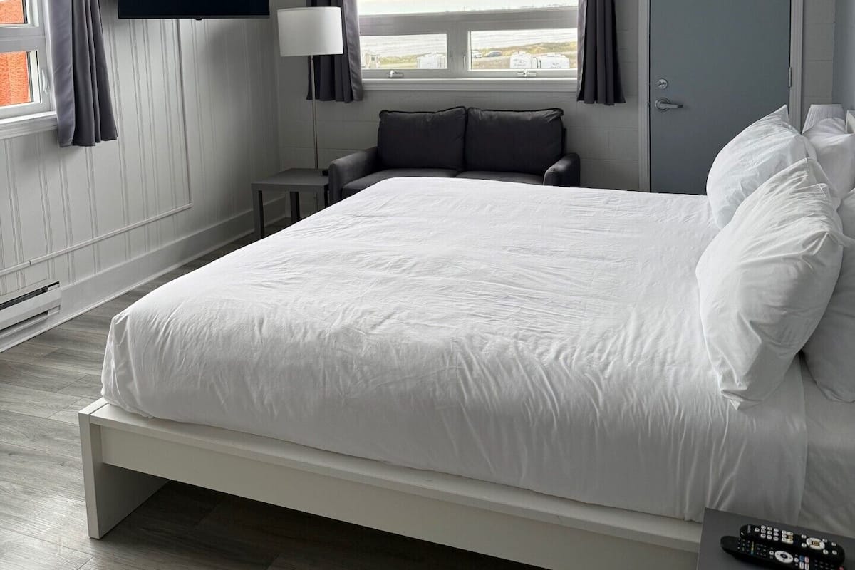 Ein Schlafzimmer mit Bett, Fernseher, Fenster und Tür.