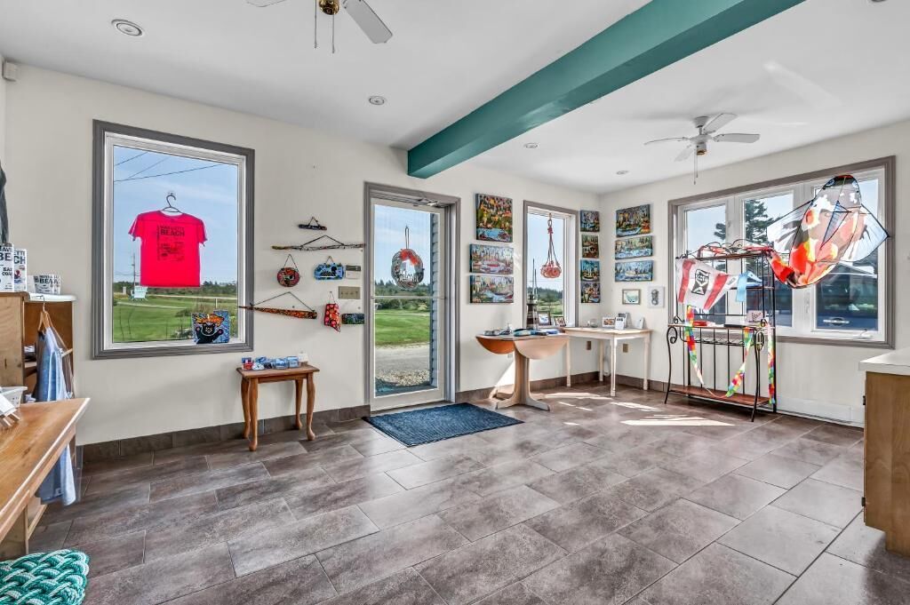 A room with a large window, a ceiling fan, a desk, and a chair.