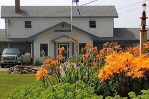 A building with a gabled roof and a small porch. There is a truck parked in front and a pile of stones to the left. - Mavillette Beach Lodge and RV Park (Mavillette)