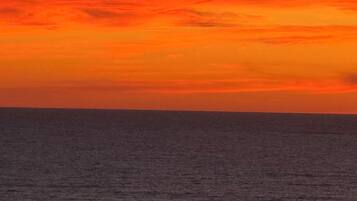 A sunset over the ocean with a view of the sea and a distant shoreline.