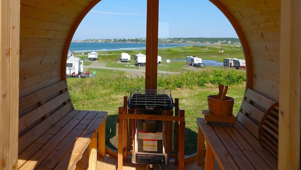 A wooden structure with an arched opening, a grill, and a table with a bowl. - Mavillette Beach Lodge and RV Park (Mavillette)