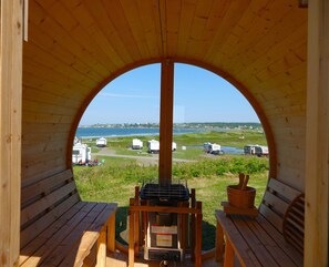 A wooden structure with an arched opening, a grill, and a table with a bowl. - Mavillette Beach Lodge and RV Park (Mavillette)