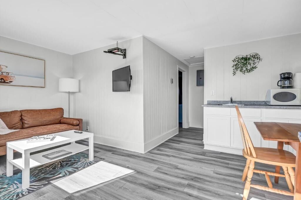 Een moderne woonruimte met een bank, salontafel en een eethoek met een tafel en stoelen.