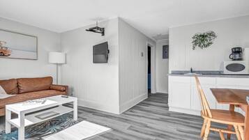 Een moderne woonruimte met een bank, salontafel en een eethoek met een tafel en stoelen.